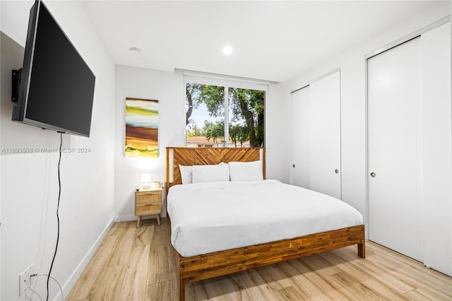 bedroom featuring light hardwood / wood-style floors and two closets