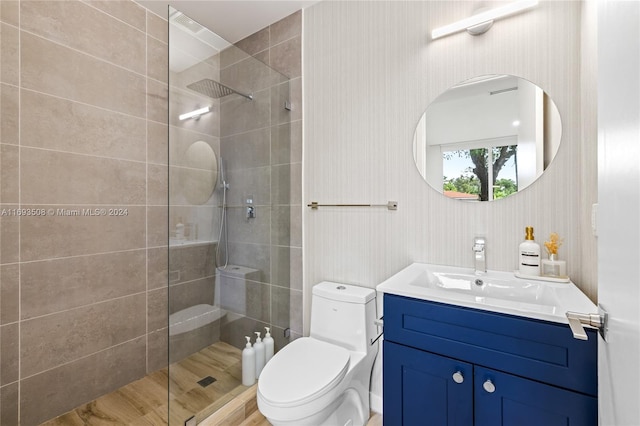 bathroom featuring hardwood / wood-style floors, vanity, toilet, and tiled shower