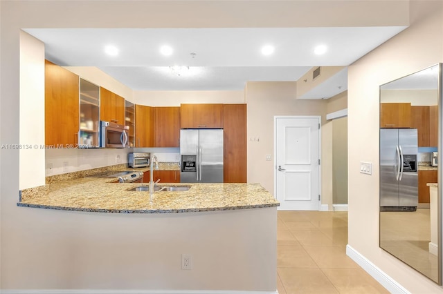 kitchen with kitchen peninsula, light stone counters, stainless steel appliances, sink, and light tile patterned floors