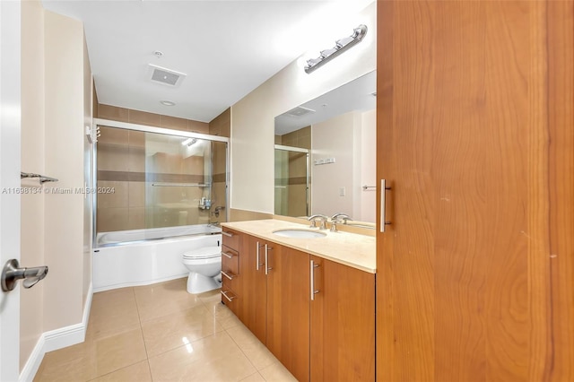 full bathroom featuring tile patterned flooring, vanity, toilet, and bath / shower combo with glass door