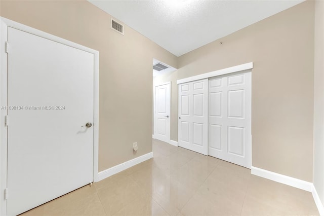 unfurnished bedroom with light tile patterned floors, a textured ceiling, and a closet