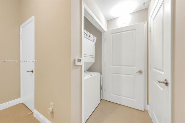 washroom with stacked washer and dryer and light tile patterned flooring