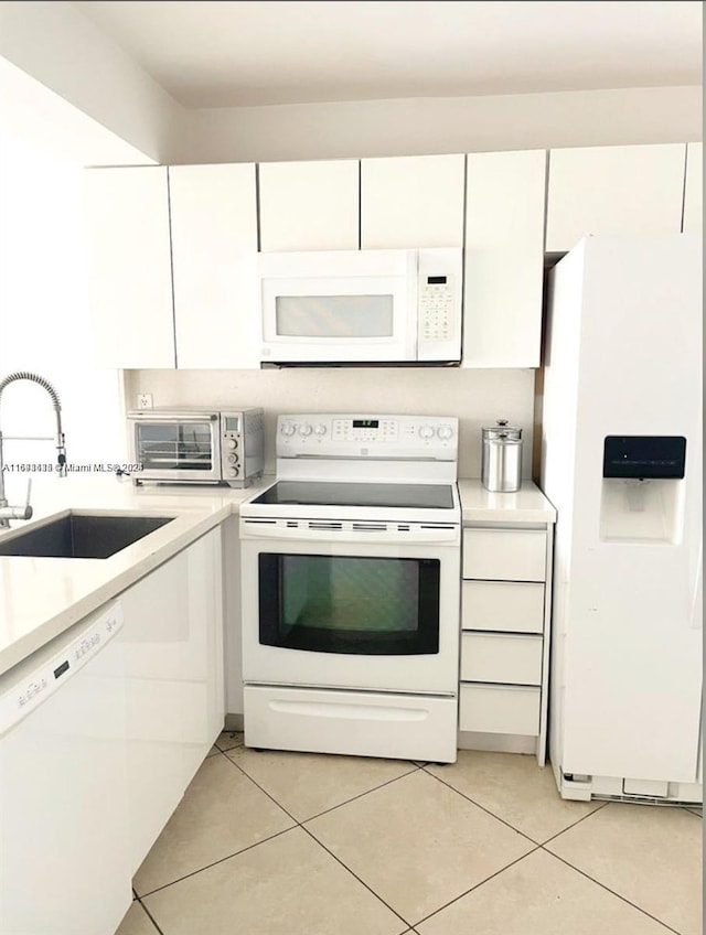 kitchen with white cabinetry, sink, light tile patterned floors, and white appliances