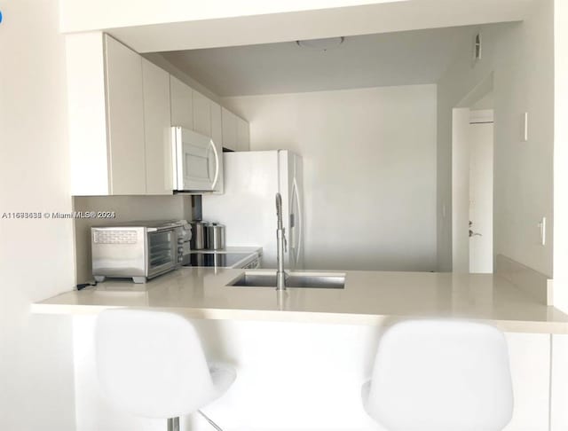 kitchen featuring sink, white appliances, and kitchen peninsula