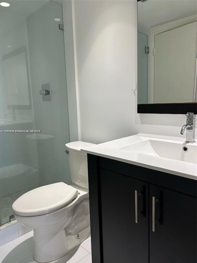 bathroom featuring tile patterned flooring, vanity, toilet, and an enclosed shower