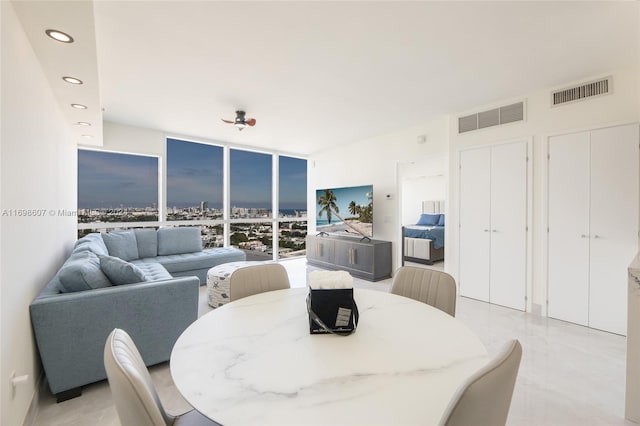 dining area with a wall of windows and ceiling fan