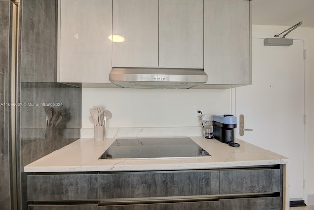 kitchen featuring black electric cooktop and light stone counters