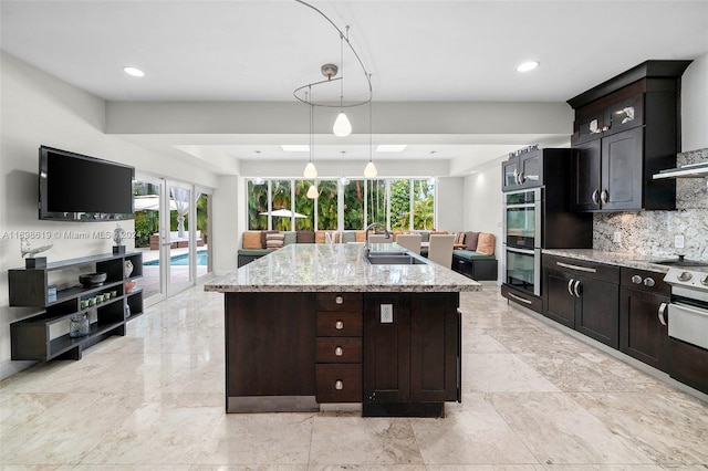 kitchen featuring dark brown cabinets, a center island with sink, a wealth of natural light, and sink