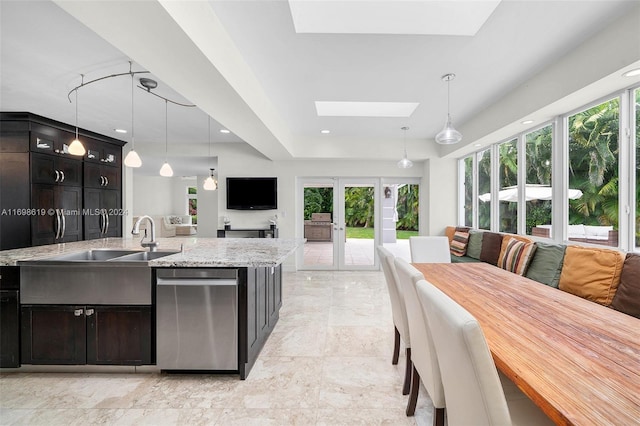 kitchen featuring a wealth of natural light, a skylight, light stone counters, and hanging light fixtures