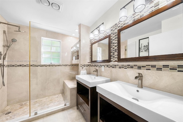 bathroom with tile patterned flooring, vanity, a tile shower, and tile walls