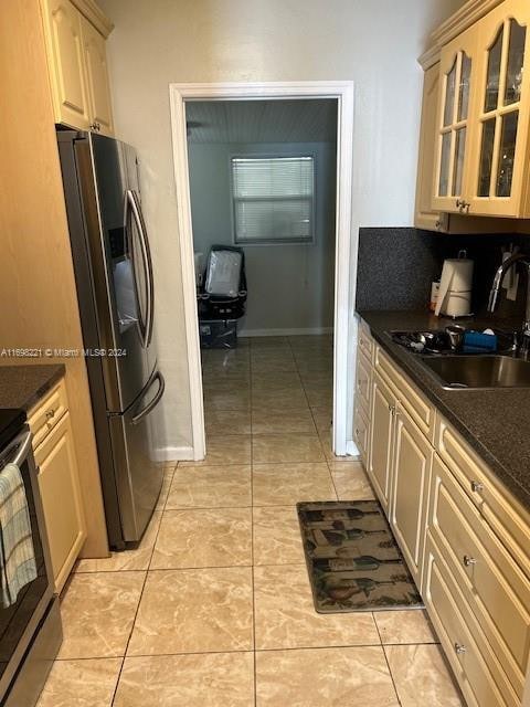 kitchen with light tile patterned flooring, appliances with stainless steel finishes, light brown cabinetry, and sink