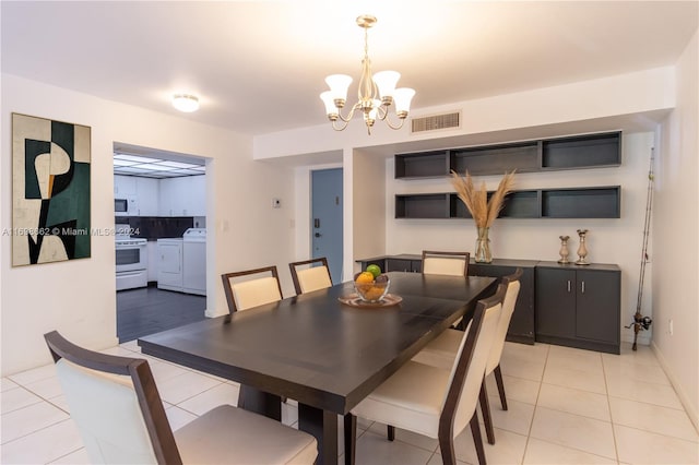 tiled dining space with washing machine and dryer and an inviting chandelier