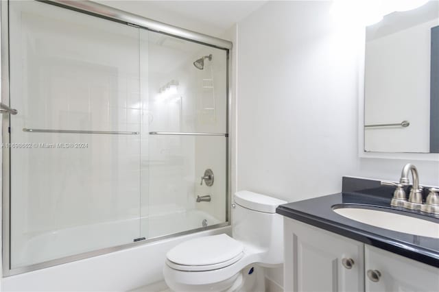 full bathroom with vanity, enclosed tub / shower combo, and toilet