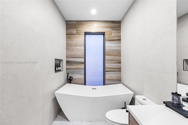 bathroom featuring vanity, toilet, tile walls, and a tub