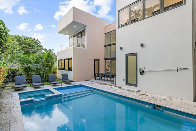 rear view of house featuring a balcony, a patio, and a pool with hot tub