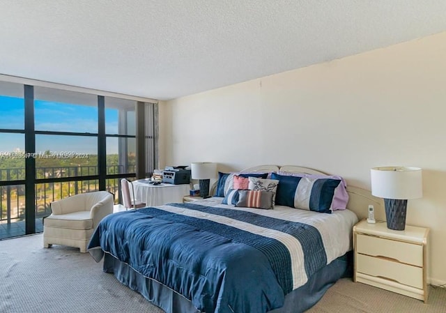 carpeted bedroom featuring a wall of windows and a textured ceiling