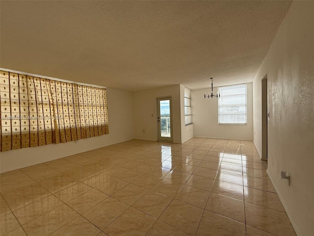 spare room featuring light tile patterned floors, a chandelier, and a textured ceiling