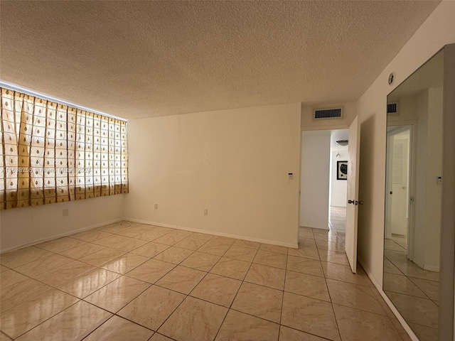 tiled spare room featuring a textured ceiling