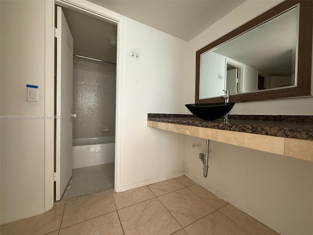 bathroom featuring tile patterned flooring, tiled shower, and sink