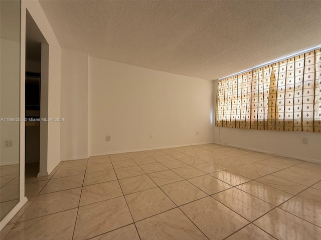 tiled empty room featuring a textured ceiling