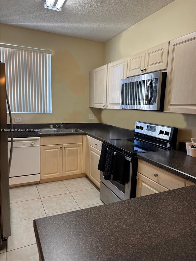 kitchen with appliances with stainless steel finishes, a textured ceiling, light tile patterned floors, and sink