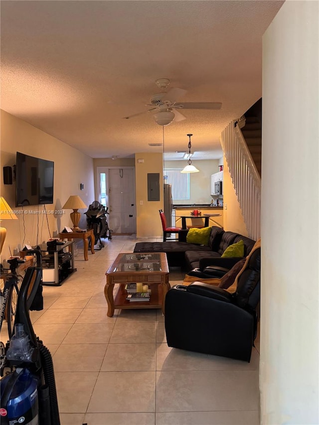 living room with electric panel, ceiling fan, light tile patterned flooring, and a textured ceiling