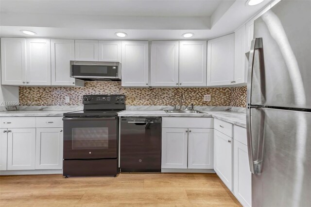 kitchen with sink, light wood-type flooring, white cabinetry, and black appliances