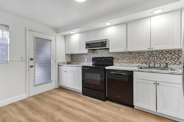 kitchen with white cabinets, sink, light hardwood / wood-style floors, and black appliances