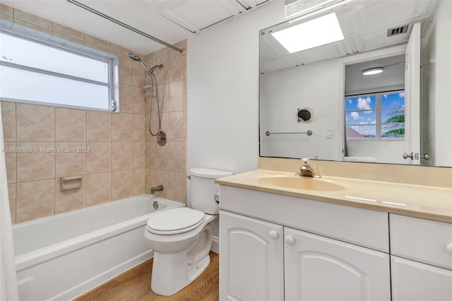 full bathroom with hardwood / wood-style floors, vanity, toilet, and tiled shower / bath