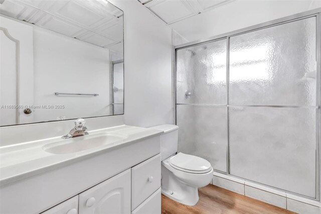 bathroom with vanity, hardwood / wood-style flooring, toilet, and a shower with door