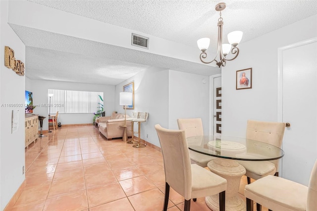 dining space with a notable chandelier, light tile patterned floors, and a textured ceiling