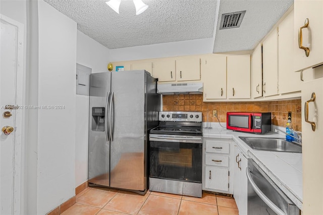 kitchen featuring sink, appliances with stainless steel finishes, tasteful backsplash, tile counters, and light tile patterned flooring