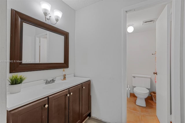 bathroom featuring tile patterned flooring, a textured ceiling, vanity, and toilet