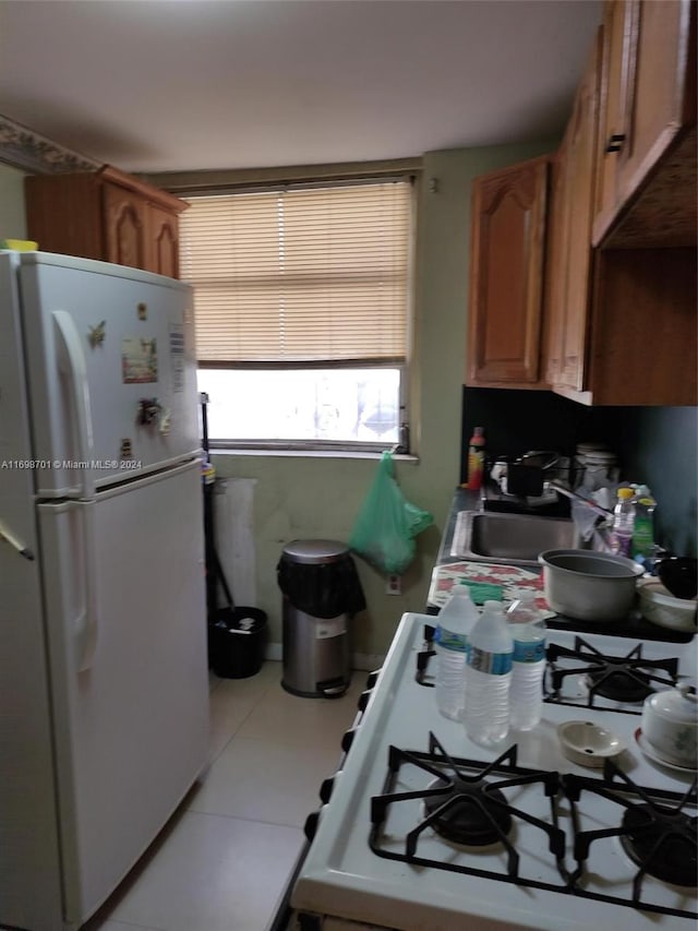 kitchen featuring light tile patterned floors, white appliances, and sink