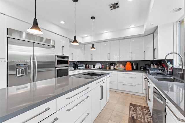 kitchen with white cabinetry, sink, stainless steel appliances, decorative light fixtures, and light tile patterned floors