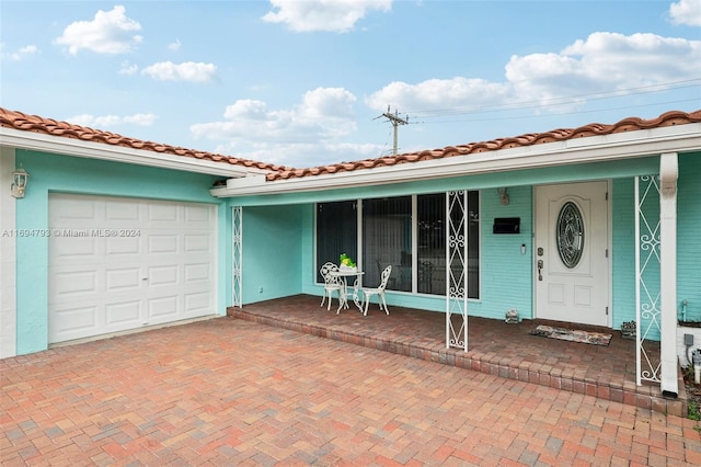 doorway to property with covered porch and a garage