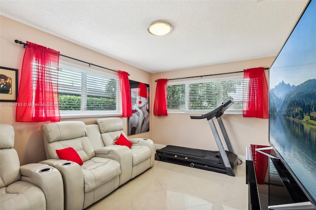 exercise area featuring light tile patterned floors, a textured ceiling, and a healthy amount of sunlight