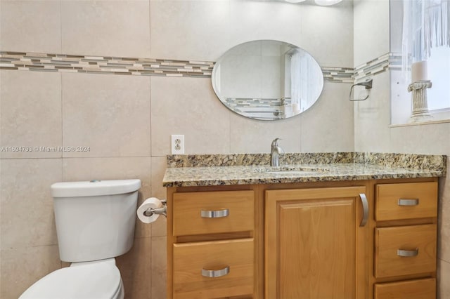 bathroom featuring vanity, toilet, and tile walls