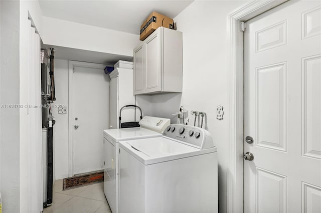 laundry area featuring cabinets, light tile patterned floors, and washing machine and dryer