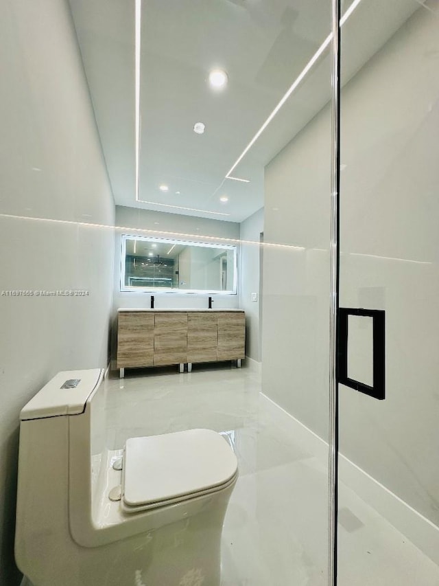 bathroom featuring vanity, a shower with shower door, and toilet