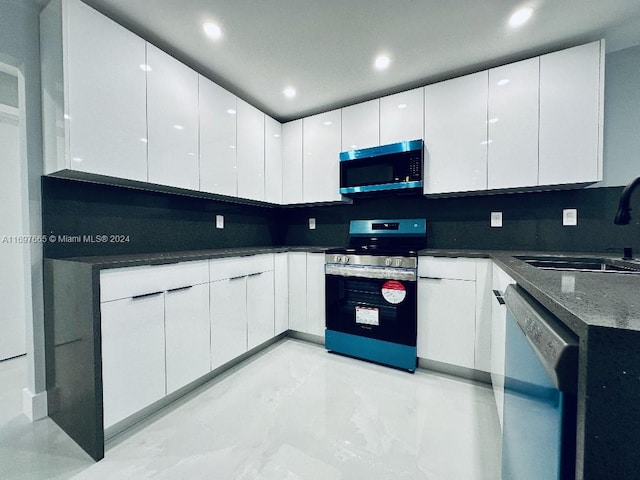 kitchen with appliances with stainless steel finishes, tasteful backsplash, white cabinetry, and sink