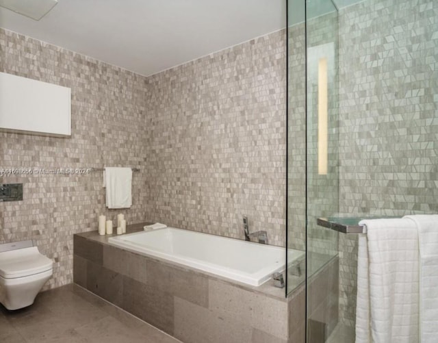 bathroom featuring tile patterned floors, separate shower and tub, toilet, and tile walls