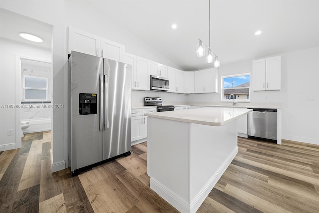 kitchen featuring white cabinetry, appliances with stainless steel finishes, lofted ceiling, a kitchen island, and hardwood / wood-style flooring