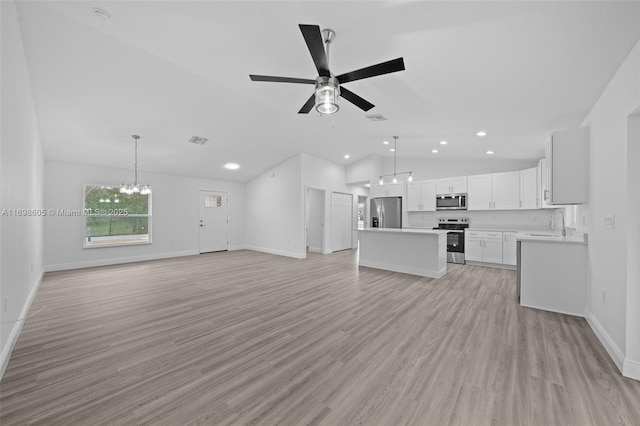 unfurnished room with ceiling fan with notable chandelier, light hardwood / wood-style floors, and vaulted ceiling