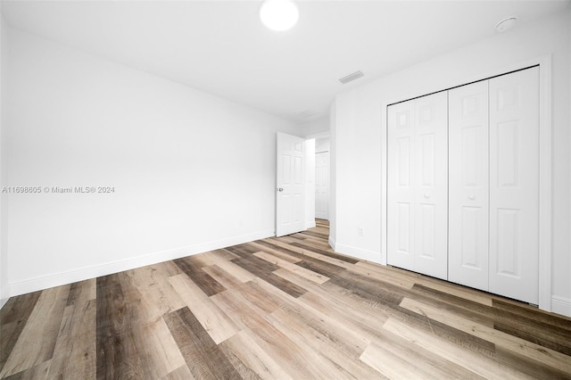 unfurnished bedroom featuring light hardwood / wood-style flooring and a closet