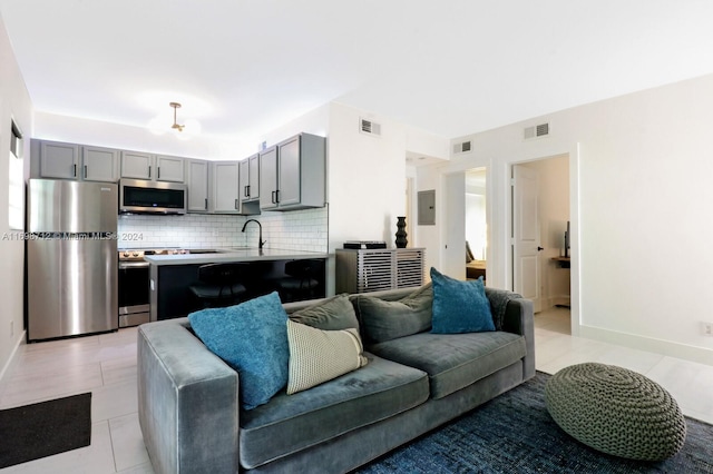 living room featuring electric panel, sink, and light tile patterned floors