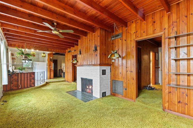 unfurnished living room featuring carpet, wood ceiling, ceiling fan, beam ceiling, and wood walls