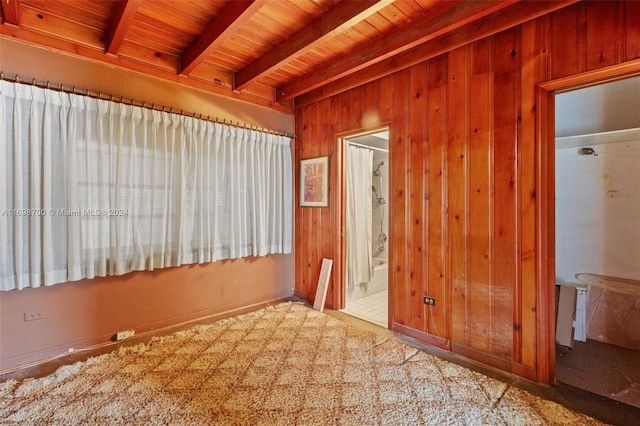 unfurnished room with beamed ceiling, wooden ceiling, and wood walls