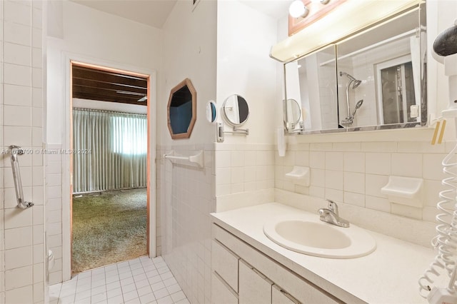 bathroom featuring tile patterned floors, vanity, a tile shower, and tile walls