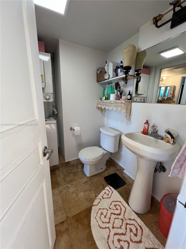 bathroom featuring toilet and stacked washer and clothes dryer